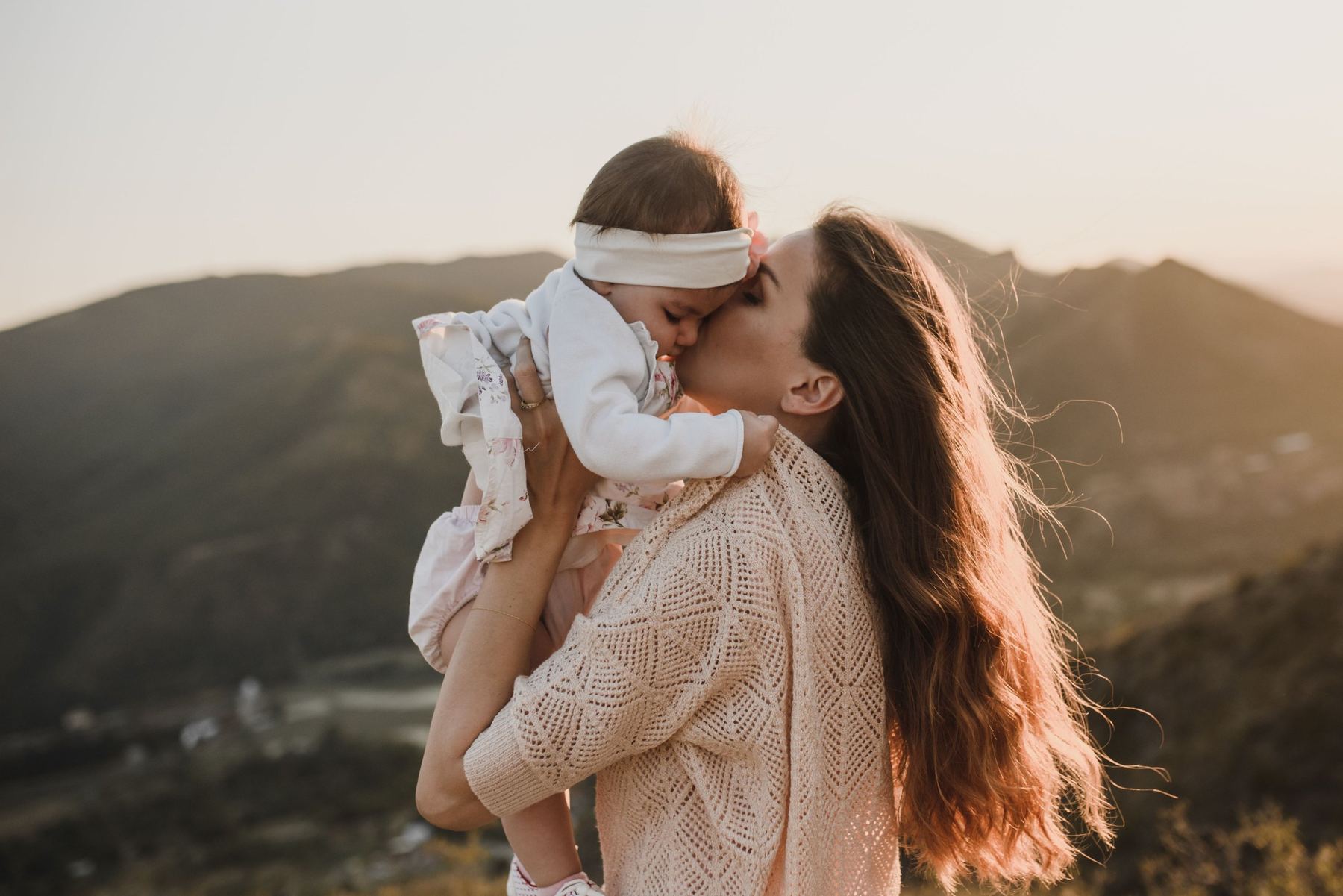 A mother lifting her baby daughter and kissing her cheek
